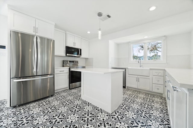 kitchen with pendant lighting, stainless steel appliances, a kitchen island, white cabinetry, and sink