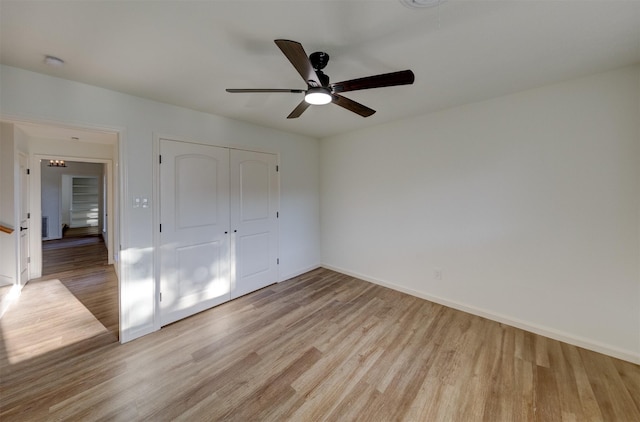 unfurnished bedroom featuring ceiling fan, a closet, and light wood-type flooring