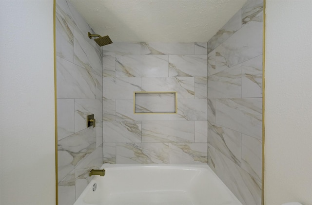 bathroom with a textured ceiling and tiled shower / bath combo