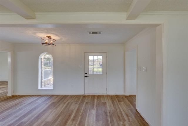 entryway with beamed ceiling, light hardwood / wood-style floors, a textured ceiling, and an inviting chandelier