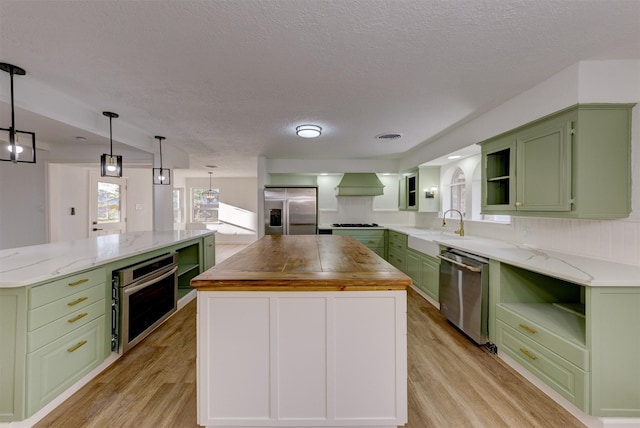 kitchen with wooden counters, green cabinets, light hardwood / wood-style flooring, appliances with stainless steel finishes, and a kitchen island