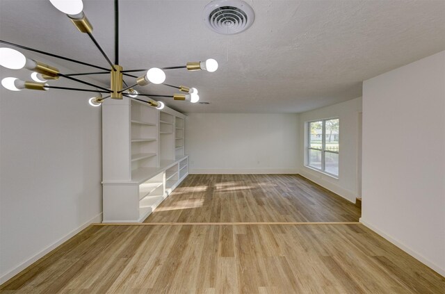 unfurnished living room featuring wood-type flooring, a textured ceiling, and a chandelier