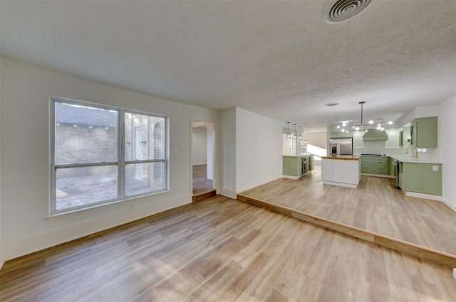 unfurnished living room with a textured ceiling, light hardwood / wood-style floors, and a notable chandelier