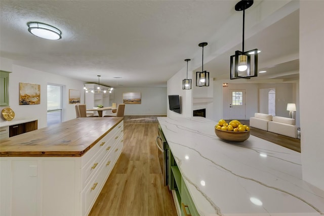 kitchen with a kitchen island, pendant lighting, white cabinetry, wooden counters, and light wood-type flooring