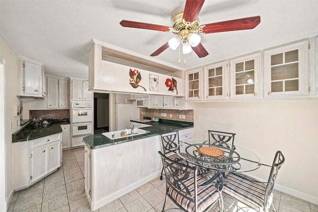 kitchen with white appliances, backsplash, white cabinetry, and sink