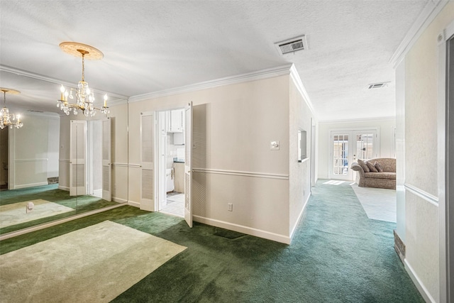 hallway featuring french doors, a chandelier, a textured ceiling, dark carpet, and ornamental molding