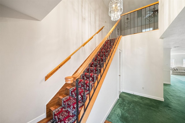 stairs with carpet, a notable chandelier, and a high ceiling