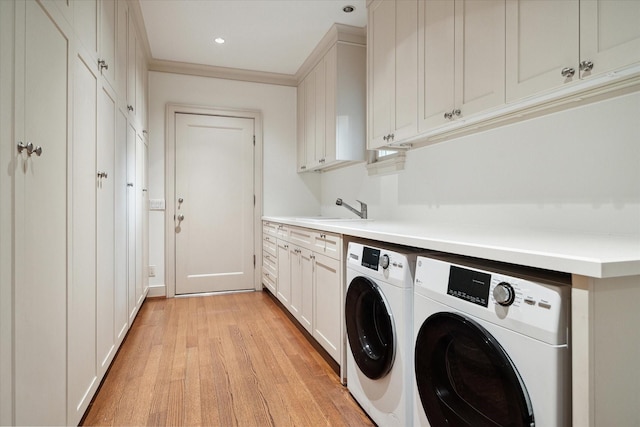 laundry area with sink, crown molding, light hardwood / wood-style flooring, cabinets, and separate washer and dryer