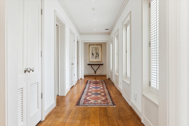 hallway with light hardwood / wood-style flooring and ornamental molding