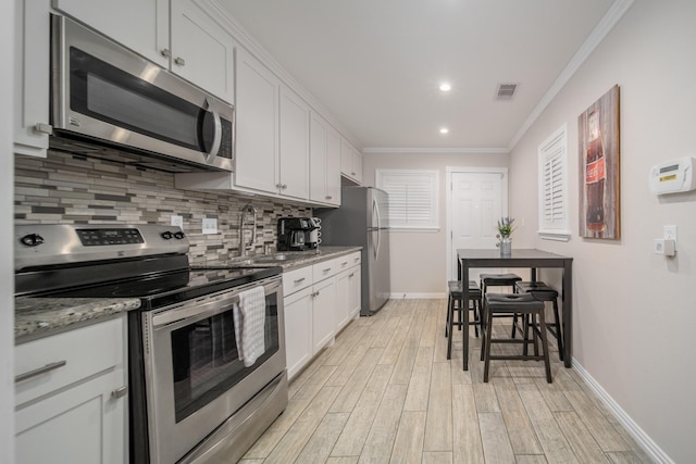 kitchen featuring light hardwood / wood-style floors, light stone countertops, white cabinetry, and appliances with stainless steel finishes