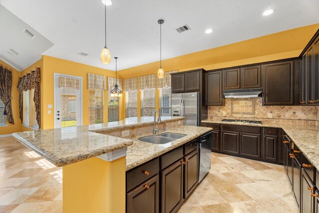 kitchen with backsplash, stainless steel appliances, sink, hanging light fixtures, and an island with sink