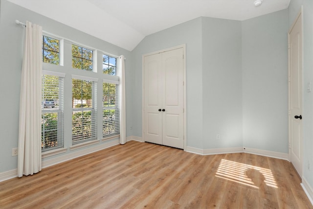 unfurnished bedroom with a closet, light hardwood / wood-style floors, and lofted ceiling