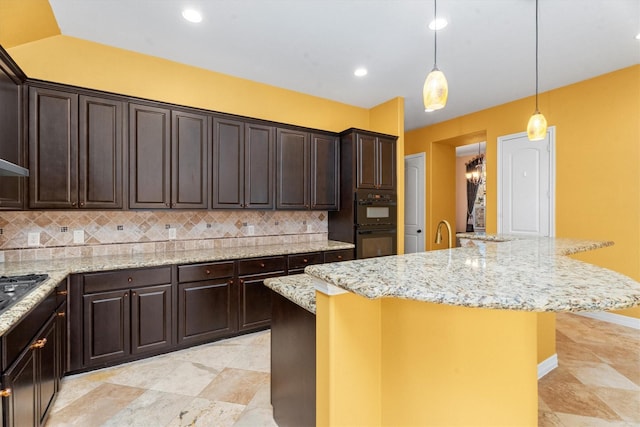 kitchen featuring decorative backsplash, dark brown cabinets, a kitchen island with sink, and decorative light fixtures