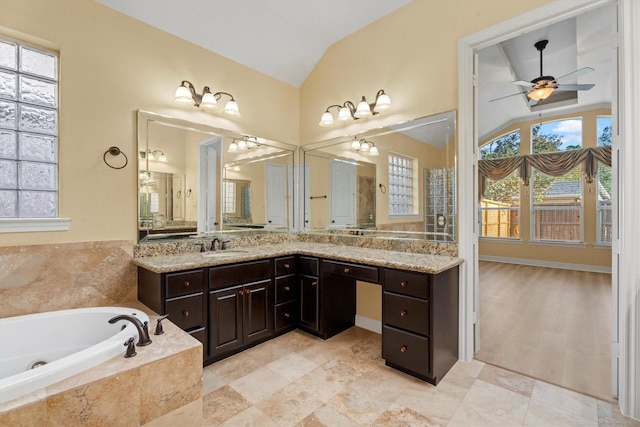 bathroom featuring a relaxing tiled tub, vanity, ceiling fan, and vaulted ceiling