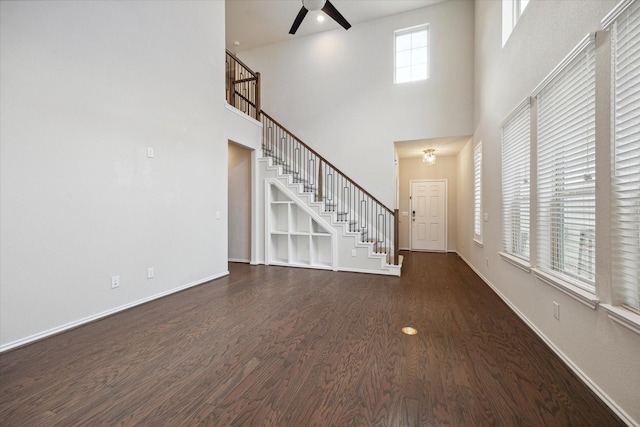 unfurnished living room featuring a high ceiling, dark hardwood / wood-style flooring, and ceiling fan