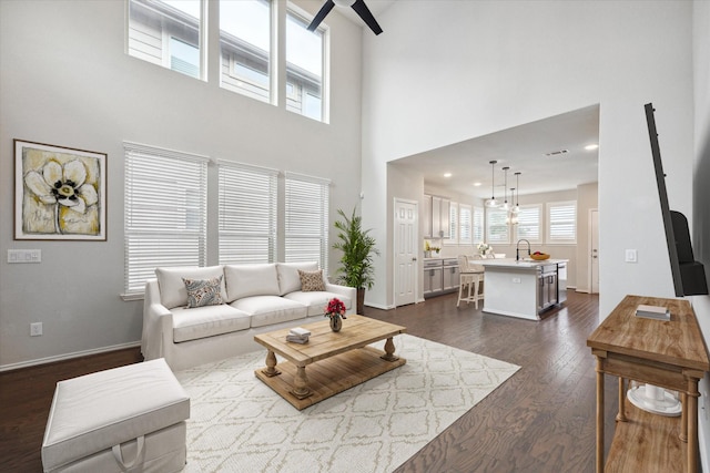 living room with ceiling fan, a high ceiling, and dark hardwood / wood-style floors