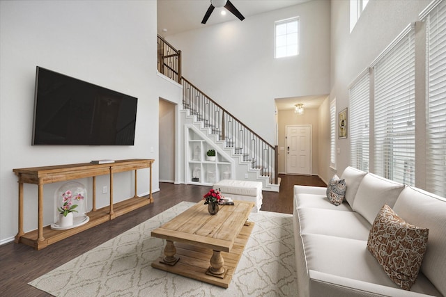 living room featuring ceiling fan, a high ceiling, and dark hardwood / wood-style floors