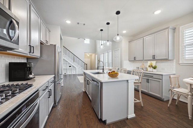 kitchen with pendant lighting, dark wood-type flooring, sink, gray cabinets, and appliances with stainless steel finishes