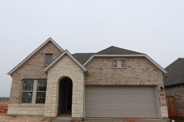 view of front of house featuring a shingled roof and brick siding