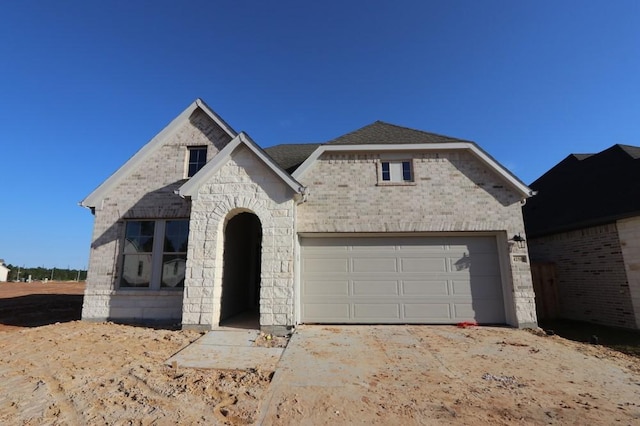 view of front of home featuring a garage, stone siding, a shingled roof, and brick siding