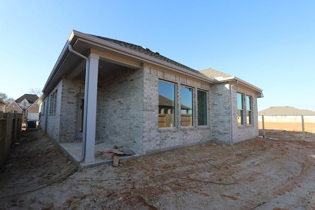 view of side of property featuring fence and brick siding