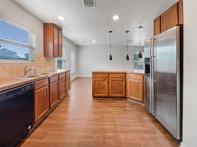 kitchen featuring high end refrigerator, black dishwasher, plenty of natural light, and hanging light fixtures