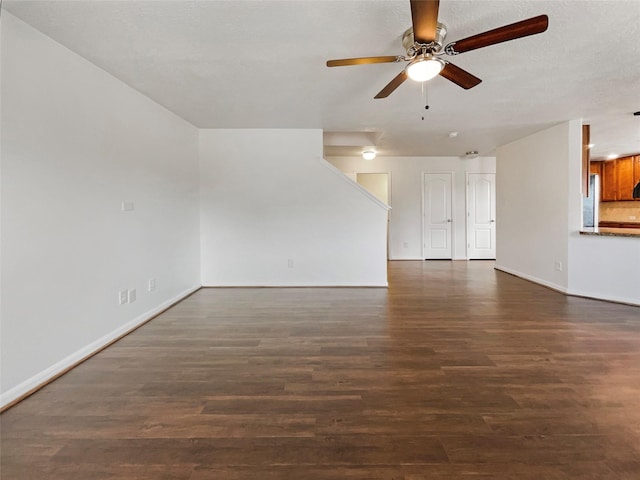 unfurnished living room with ceiling fan, dark wood-type flooring, and a textured ceiling