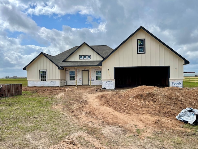 modern farmhouse featuring a garage, a shingled roof, and board and batten siding