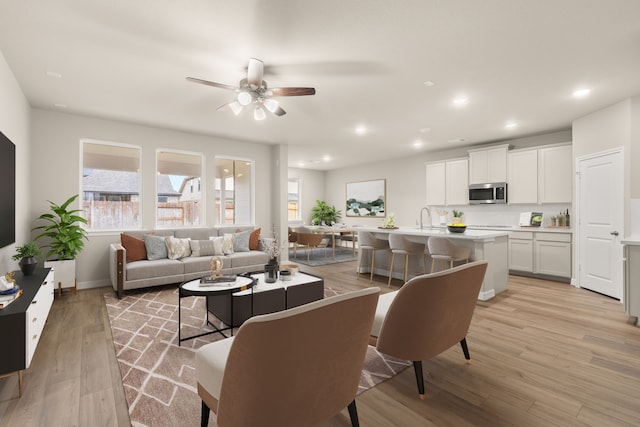 living room with ceiling fan, light wood-type flooring, and sink