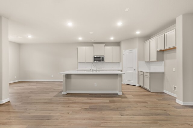 kitchen featuring a kitchen island with sink, sink, and light hardwood / wood-style floors