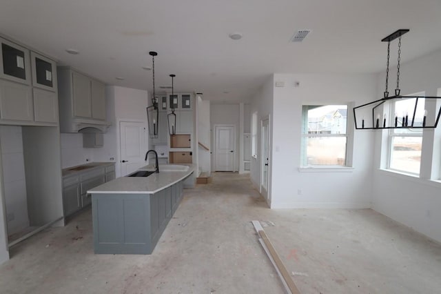 kitchen with sink, an island with sink, gray cabinetry, and hanging light fixtures