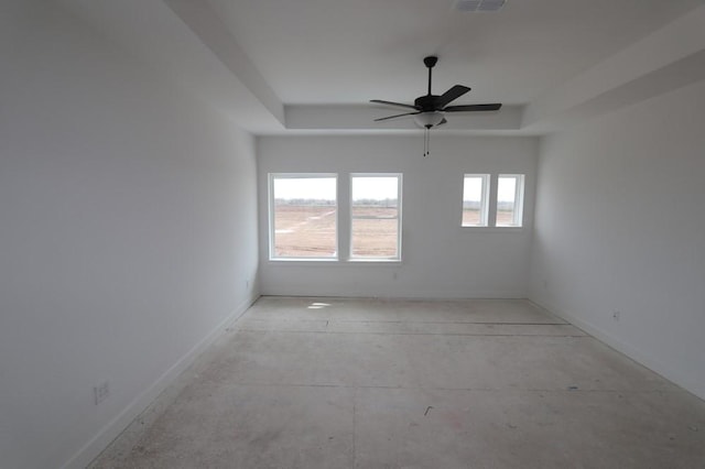 spare room with ceiling fan and a raised ceiling