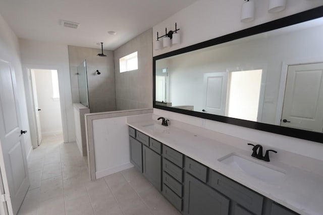 bathroom featuring tile patterned floors, tiled shower, and vanity