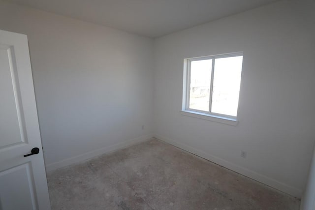 spare room with concrete flooring and baseboards