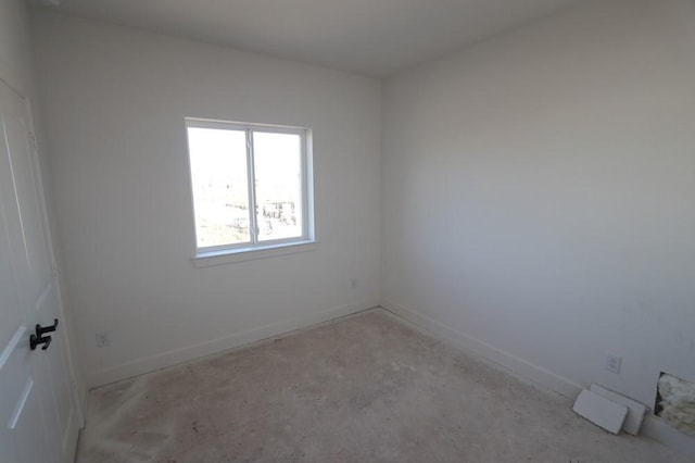 spare room featuring unfinished concrete floors and baseboards