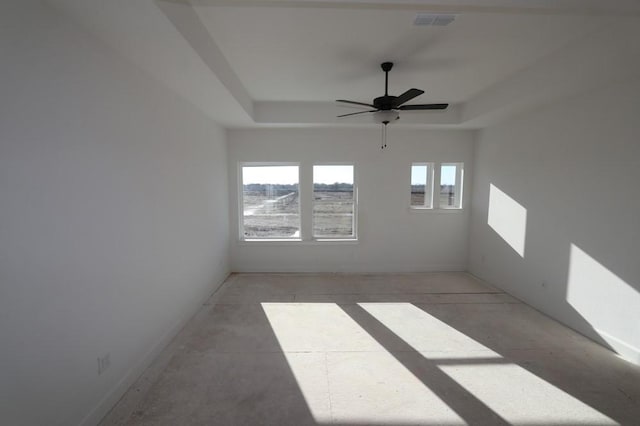 spare room featuring a ceiling fan, a tray ceiling, and visible vents