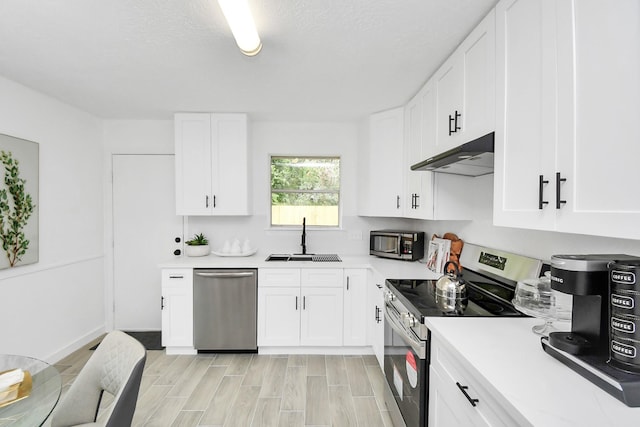 kitchen with white cabinetry, sink, a textured ceiling, appliances with stainless steel finishes, and light wood-type flooring