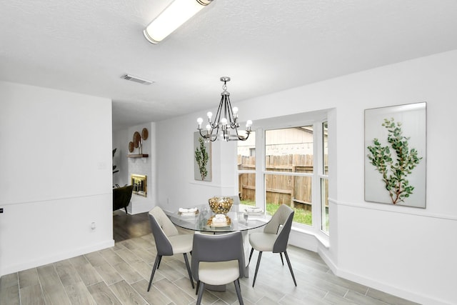 dining space featuring a textured ceiling, a notable chandelier, and light wood-type flooring