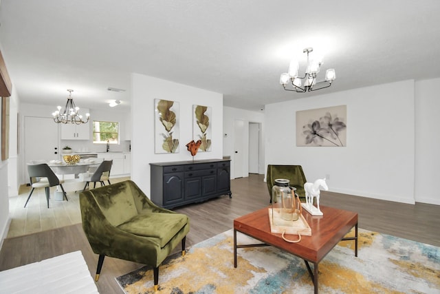 living room with light hardwood / wood-style floors, an inviting chandelier, and sink