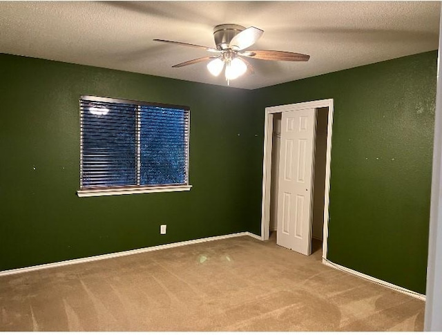 unfurnished bedroom featuring ceiling fan, a closet, carpet, and a textured ceiling