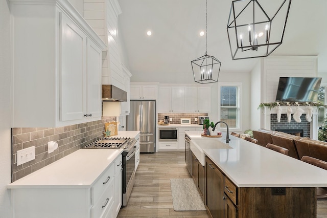 kitchen with sink, stainless steel appliances, an island with sink, light hardwood / wood-style floors, and white cabinets