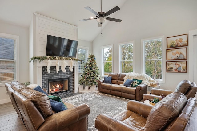 living room featuring ceiling fan, a fireplace, high vaulted ceiling, and light hardwood / wood-style floors