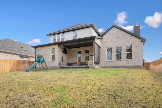 back of house featuring a playground, ceiling fan, and a lawn