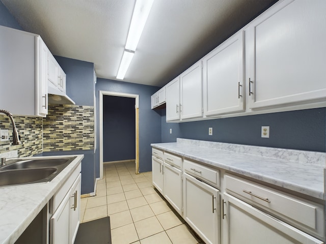 kitchen featuring white cabinetry, sink, light stone countertops, backsplash, and light tile patterned floors