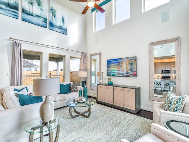 living room with hardwood / wood-style floors, a towering ceiling, and ceiling fan