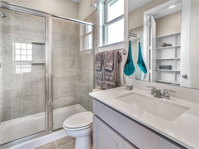 bathroom featuring tile patterned flooring, vanity, a shower with shower door, and toilet