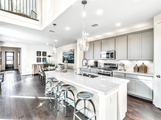 kitchen featuring sink, dark hardwood / wood-style flooring, pendant lighting, gray cabinets, and appliances with stainless steel finishes