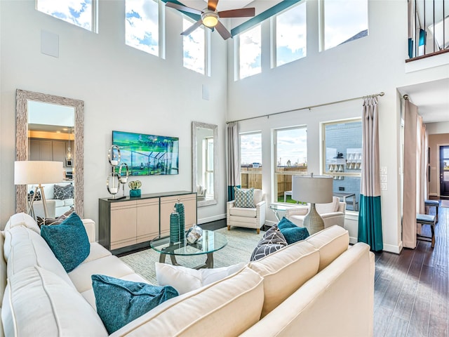 living room featuring a towering ceiling, ceiling fan, and dark wood-type flooring