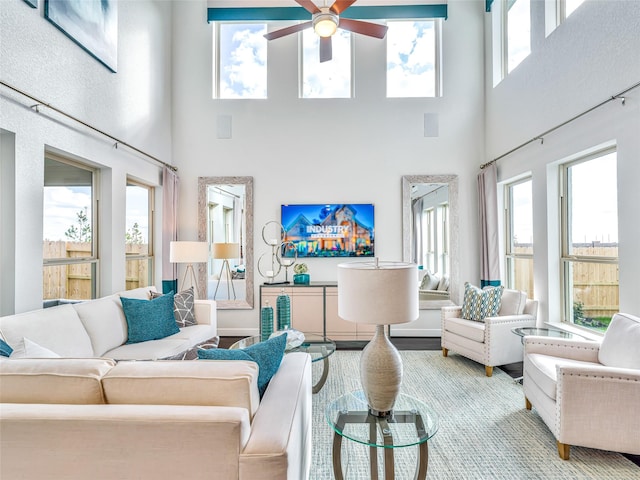 living room featuring ceiling fan, a towering ceiling, and wood-type flooring