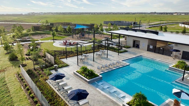 view of swimming pool with a rural view and a patio